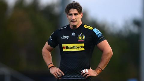 Tom Hendrickson stands with hands on hips during a pause in a game for Exeter