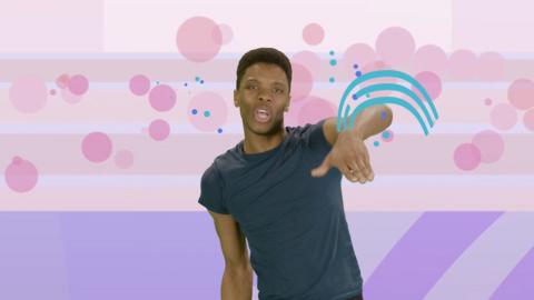 Presenter Rhys Stephenson with one hand in the air. Backdrop is of a purple sports pitch.