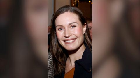 A woman smiling, with long dark hair.
