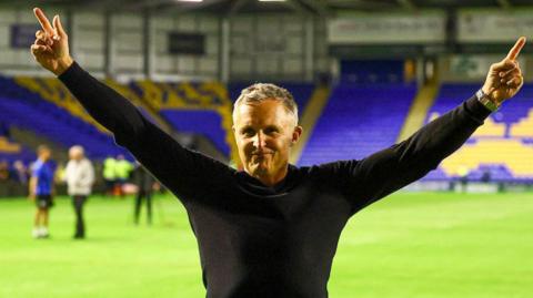 Paul Rowley celebrating with his arms aloft after a match.