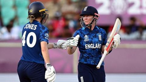 Amy Jones of England (left) touches gloves with team mate Heather Knight while batting vs New Zealand