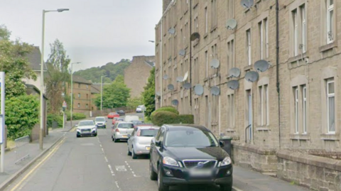 A residential street with flats on one side and a park on the other