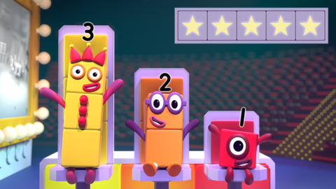 Promo image for Numberblocks: See the Amount game, three characters numbered 3, 2 and 1, are smiling at the audience in a theatre.