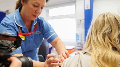 A healthcare worker administers a flu jab to another person in a healthcare environment at Ulster hospital in Belfast on 4 December.