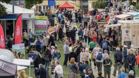 Crowds of people walking around food stall at the food festival.