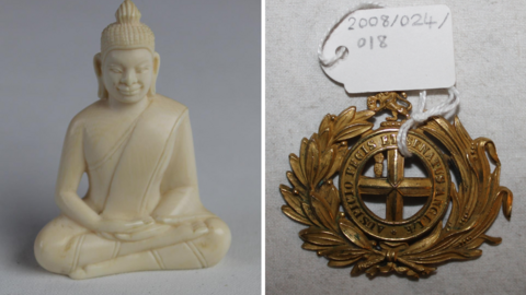 A carved ivory buddha with robes in a cross-legged position. It sits next to a circular belt buckle with a laurel motif with the words "Auspicio Regis et Senatus Angliae".