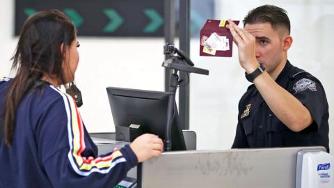 A US CBP officer checks the passport of a traveller