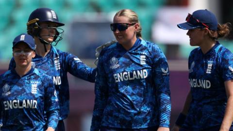 Sophie Ecclestone grimaces while being congratulated by team-mates for taking a wicket