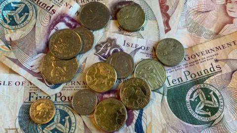 Manx money, notes and coins, laid flat on a table.