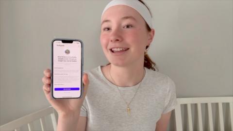 Teenage girl holding up phone with her blocked Instagram account