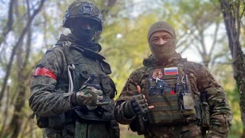 David Kuloba and a Russian soldier in full combat gear pose for the camera in a forest