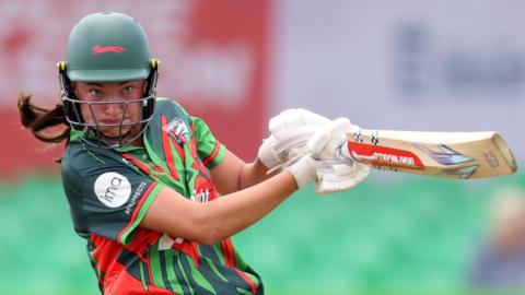 Francesca Sweet wearing a helmet swings her bat playing for Leicestershire
