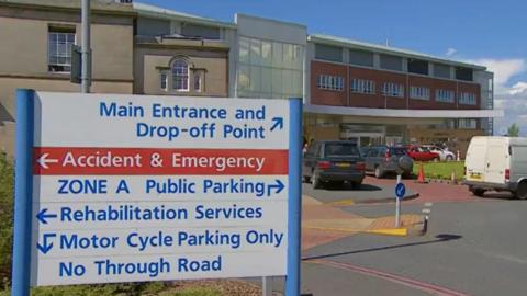 A general view of the entrance to the Cumberland Infirmary in Carlisle. A sign with directions to the various departments is in the foreground, with the main entrance behind it.