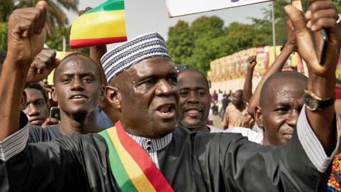 Mamadou Hawa Gassama, wearing a sash in the green, yellow and red colours of Mali's flag, takes part in a demonstration in Bamako, Mali - 2018