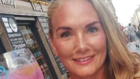 Carly Wealleans smiles at the camera. She has long blonde hair and blue eyes.