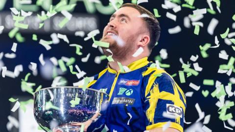 Luke Littler celebrates with Grand Slam of Darts trophy