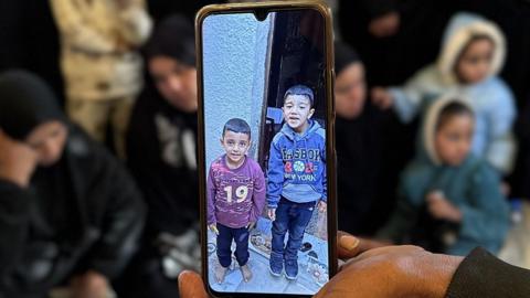 An image of two young boys on a phone.