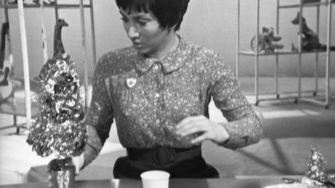 Valarie Singleton sits at a table with a mini Christmas tree on it