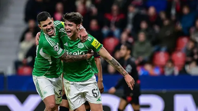 Lewis Miley of Newcastle United celebrates with Bruno Guimaraes after scoring against Bayer Leverkusen