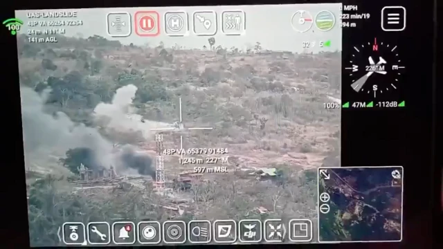 A drone feed, including a heads up display with lots of symbols, coordinates and target crosshairs, showing a crane with smoke near it.