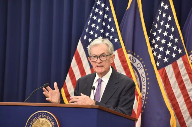 US Federal Reserve Chairman Jerome Powell delivers remarks at a news conference. He is standing behind a podium and in front id US flags