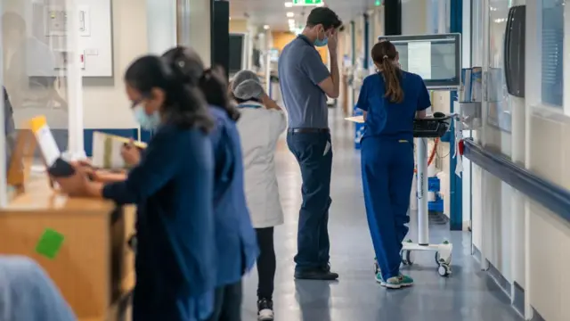 Doctors and hospital staff stand in a busy corridor of a hospital