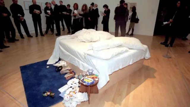 Tracy Emin's My Bed is an unmade bed, with a blue rug next to it and litter strewn around
