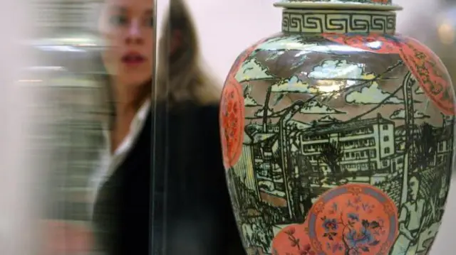 A green and red pot, with an urban scene depicted on it