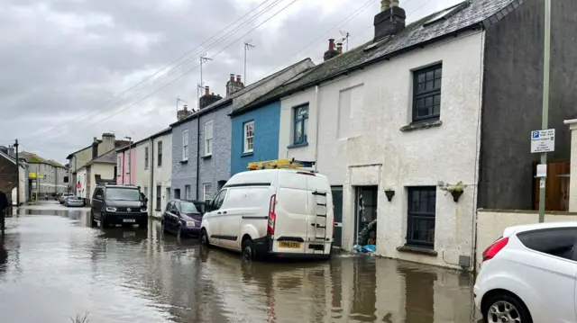 A street showing the extend of flooding - the cars are up to their wheels in water.