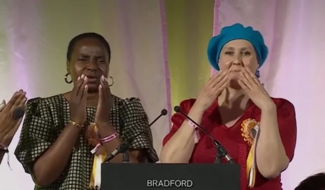 Nnena Kalu and Charlotte Hollinshead blowing kisses from behind a podium