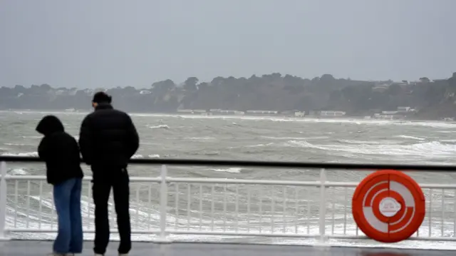 Two people face away from the camera and out to sea issued a "danger to life" rain weather warning in parts of Wales and South West England