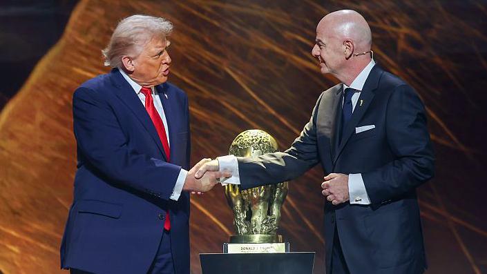 Donald Trump and Gianni Infantino shake hands in front of the Fifa peace prize trophy