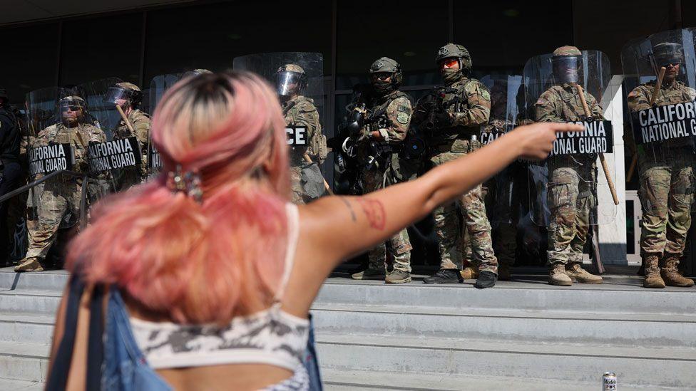 A protestor with pink hair points at guards as they confront the California National Guard as they protect the Federal Building during protests sparked by immigration raids in Los Angeles, California, USA, on 9 June 2025.