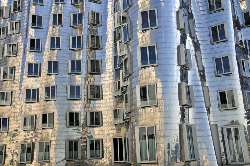 Der Neue Zollhof building in Düsseldorf, Germany - the photograph is a close-up of the buildings stainless-steel facade lined with windows of varying sizes