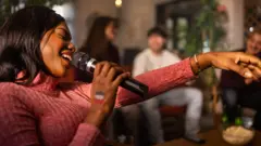 Woman dey sing for karaoke club