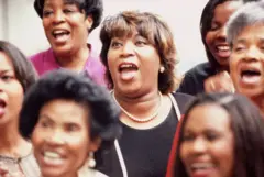 os rostos de sete mulheres cantando em um coral de gospel