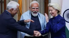 Tres líderes de pie y sonrientes. El del centro es el primer ministro indio, Narendra Modi, a la izquierda está Antonio Costa, presidente del Consejo Europeo, y la derecha Ursual von der Leyen, presidenta de la Comisión Europea.