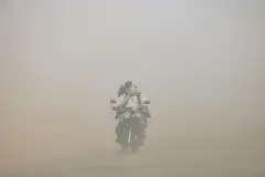 یک مرد موتور سوار در طوفان گرد و خاک