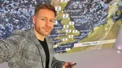 Tomasz Schafernaker na tle mapy pogody.