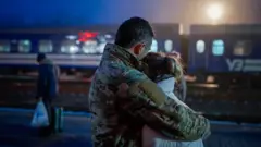 Мужчина в военной форме обнимает девушку перед отправлением поезда