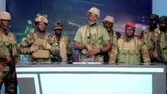 Ọmogun mẹjọ duro lẹyin tabili ikaroyin nileeṣẹ tẹlifisan orilẹede Benin lọjọ keje oṣu Kejila yii