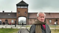 Саймон Шама на фоне главного барака Освенцима