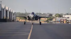 Bir f35 uçağı hangardan çıkmış runway'de görünüyor.