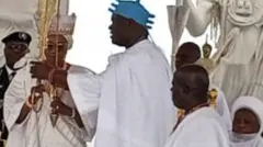 Ọba Adeyeye Enitan Ogunwusi tó wọ aṣọ funfun àti adé aláwọ̀ búlúù ń gbé ọ̀pá àṣẹ aláwọ̀ Goolu fún aya ààrẹ Naijiria, Oluremi Tinubu ẹni tó wọ aṣọ oke ìró àti buba aláwọ̀ funfun, to si de adé funfun bakanna.