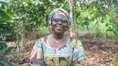 TANON GOUMAN THÉRÈSE EPSE Siéto fixant l'objectif alors qu'elle est dans une plantation de cacaoyers