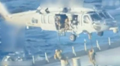 Bir helikopter kamuflajlı askleri gemiye indiriyor