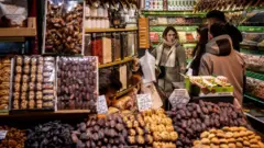 İstanbul'da kuruyemiş dükkanında alışveriş yapan birkaç kadın. üzerilerinde kışlık kıyafetler, kaban ve atkı var.