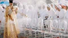 ወርቃዊ ልብሲ ተኸዲኑ ዕጣን ዝዓጥን ኣብ ቅድሚ ድንን ኢለን ጸሎተን ዘስምዓ ጻዕዳ ክዳን ዝለበሳን ዝተጎልበባን ደቂኣንስሰትዮ