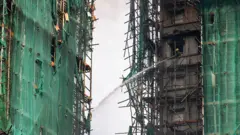 2025年11月27日,香港大埔区宏福苑,一名消防员正用水枪扑灭仍在燃烧的住宅大楼。