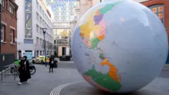 Turner Ödüllü sanatçı Mark Wallinger'ın London School of Economics kampüsünde sergilenen "Tersine Dönmüş Dünya" adlı eseri, ters çevrilmiş siyasi bir Dünya küresi heykeli. Yapı Kuzey Kutbu üzerinde duran bir küreyi tasvir ediyor ve Mart 2019'da açıldı.